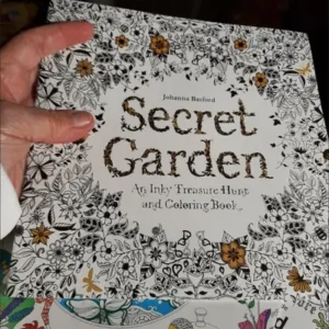 A hand is holding onto the cover of an adult coloring book.