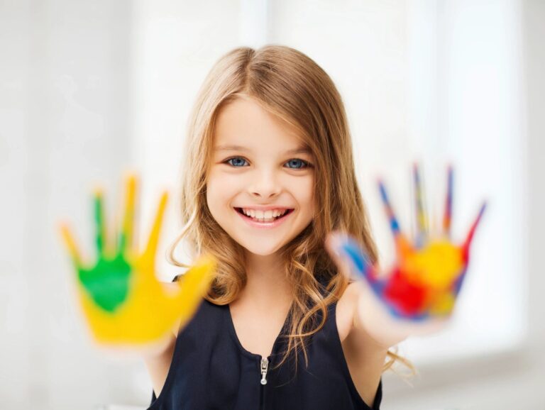 A little girl with her hands painted in different colors.