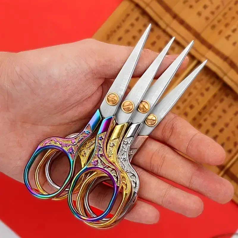 A person holding four pairs of scissors in their hand.